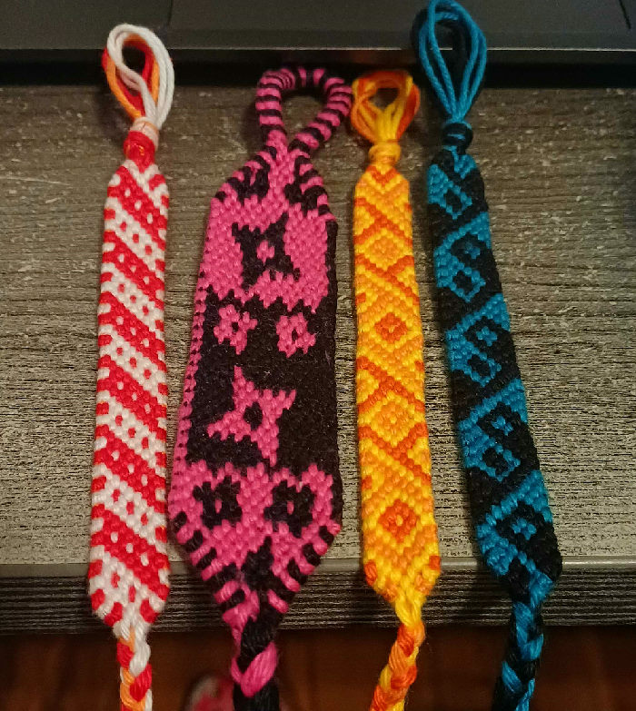 4 bracelets. white and red, pink and black, oranges, dark teal and black.
